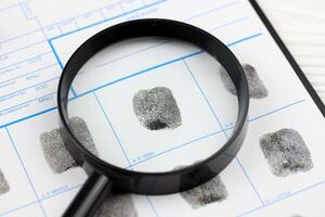 Fingerprints card police form on A4 tablet lies on office table with pen and magnifying glass photo