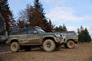 Automobile in a countryside landscape with a mud road. Off-road 4x4 suv automobile with ditry body after drive in muddy road photo