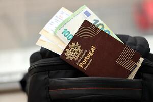 Red Portugal passport of European Union with money and airline tickets on touristic backpack photo