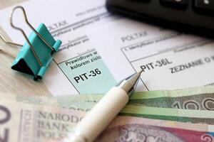 Declaration of the amount of earned income or incurred loss, PIT-36 and PIT-36L tax forms on accountant table with pen and polish zloty money bills photo