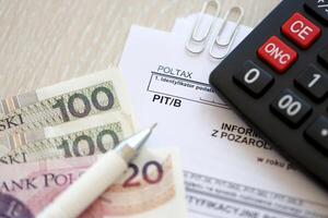 Information on amount of income or loss from non-agricultural economic activity, PIT-B form on accountant table with pen and polish zloty money bills photo