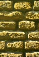 Vertical wall texture of several rows of very old brickwork made of red brick. Shattered and damaged brick wall with pinched corners photo