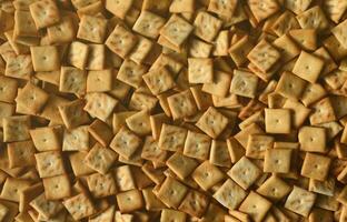 Background texture of small edible squares baked from dough and sprinkled with salt. A lot of salt cracker photo