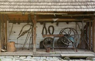 Collection of planers and retro wood saws hang on a wooden wall near an old house. Carpenters plane and other things on wall photo