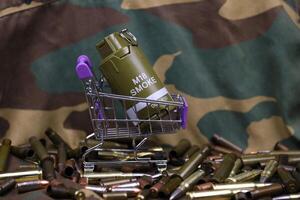Rifle cartridges in small shopping cart. Big caliber ammo cartridges and hand grenades with a small shopping basket photo