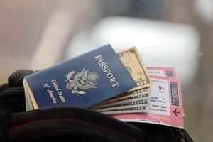 Blue United States of America passport with money and airline tickets on touristic backpack photo