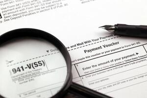 IRS Form 941-V Payment Voucher blank on A4 tablet lies on office table with pen and magnifying glass photo