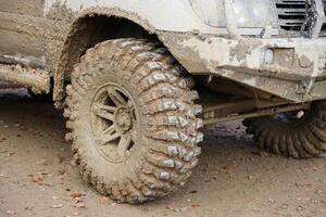 Wheel closeup in a countryside landscape with a mud road. Off-road 4x4 suv automobile with ditry body after drive in muddy road photo