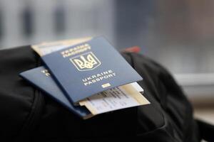 Two ukrainian biometrical passports with air flight tickets on black touristic backpack photo