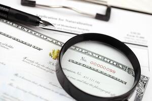 N-400 Application for Naturalization and Certificate of naturalization on A4 tablet lies on office table with pen and magnifying glass photo