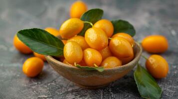 Ripe kumquats in a bowl with fresh leaves offering a healthy citrus treat photo