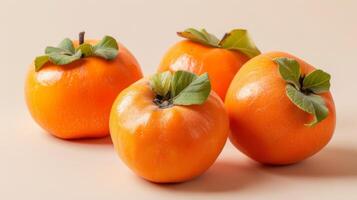 Close-up of three fresh, ripe, vibrant persimmons with juicy texture and green leaves photo