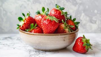 Strawberry freshness in a bowl with ripe red juicy organic fruits on a marble background photo