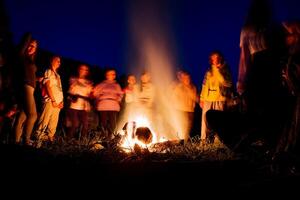 personas en un borroso antecedentes danza a noche por el fuego, un fuego espectáculo, bailando con un pandereta, chamánico rituales en naturaleza, noche bailes, un grande fuego de leña. foto