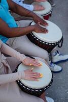 calle músicos jugando africano djembe batería, manos de cerca participación un tambor cubierta, un niña con un hermosa manicura, De las mujeres manos, un africano americano. foto
