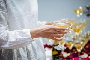 Glasses of champagne in the hands of a waitress girl, light sparkling wine, distribution of glasses with whiskey, cocktail party, alcoholic beverages spill photo