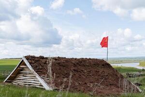 A camouflaged command post of the Soviet army, a dugout for shelter from artillery shelling, the red flag of the Russian army, the construction of the Great Patriotic War, a bomb shelter. photo