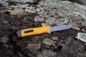 A bushcraft survival knife lies on a stone, a gray natural background of moss, the fire is hidden in the handle of the knife. photo