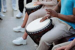 calle músicos jugar batería, de los hombres manos de un negro chico golpear el cubierta de un percusión instrumento, percusión en el calle. foto