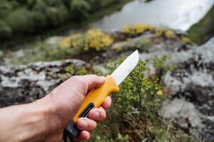 un del hombre mano sostiene un agudo cuchillo para supervivencia en naturaleza, un del hombre mano agarre un espada es un firma apretón de un cuchillo. foto