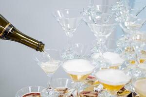 A pyramid of champagne glasses, pour a drink of wine into glasses, white foam, transparent crystal glass. photo