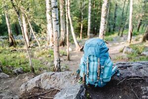 un grande azul mochila con cosas para excursionismo en el montañas, un turista cuenco para equipo, un bolso para que lleva equipo, eslingas, aprietes, bolsillos relleno con alimento. foto