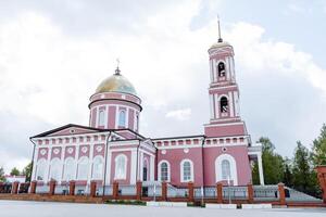 ortodoxo Iglesia en el ciudad de birsk Rusia bashkortostán, un sitio de peregrinaje para cristianos, un campana torre con un pico en el techo, un rosado edificio. foto