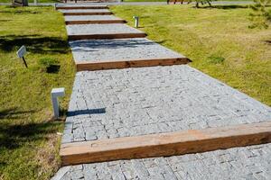 The staircase is made of paving stones, stone blocks are laid in even rows, the pedestrian zone in the city park, the design of the terrain on the landscape, do not walk on the lawn. photo