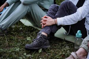 Hiking in the forest, a person sitting on the ground, hugging his hands with his noks, bent knees, boots for a hike, sitting together by the fire. photo