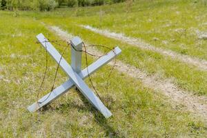 An anti-tank hedgehog, barbed wire wound on a wooden cross, an anti-personnel barrier, a military obstacle. photo