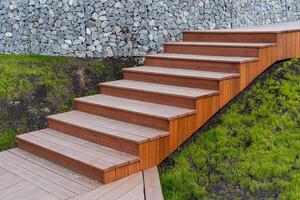 de madera escalera ensamblado desde tableros, paisaje diseño en un privado casa, marrón escalera, descendencia arriba el pasos, verde césped césped. foto