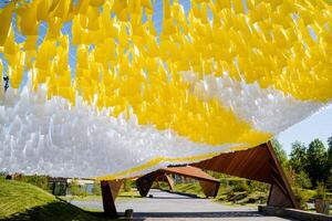 decoración de el ciudad parque, amarillo cintas colgando terminado el peatonal camino, paneles de labor de retazos piezas de tela, blanco color, balanceo en el viento. foto