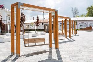 al aire libre columpios de moderno diseño, un pueblo cuadrado, un sitio de descanso para los ciudadanos, de madera bancos, balanceo en cadenas, un diversión parque. foto