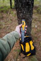 A bushcraft knife lies in a man's hand, a tactical knife with a plastic handle in the sheath, a yellow handle. photo
