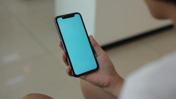 Hand holding smartphone blue screen video
