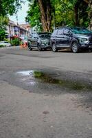 Central Jakarta, January 30, 2024 - puddles of water in the middle of the highway, with cars parked on the side of the road. photo