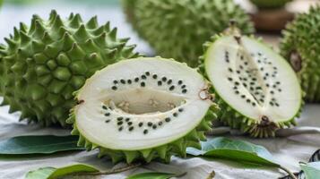 Fresh cut half of ripe green soursop fruit with seeds on a tablecloth showing tropical exotic texture photo