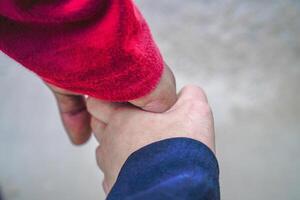 the hands of a couple holding hands against the background of beach sand. photo