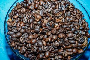 negro café frijoles en un transparente vaso bol, en un verde mesa. foto