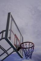 Close-up view of a basketball basket against a cloudy sky background. photo