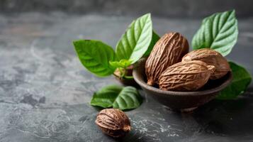 Close-up of betel nuts and green leaves in a rustic ceramic bowl on a textured dark background photo