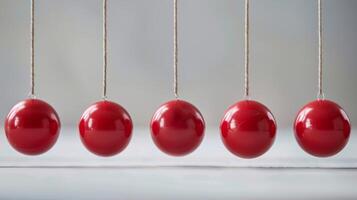 Newton's cradle with red balls demonstrating physics concepts of momentum, kinetic energy, and conservation photo