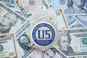 KYIV, UKRAINE - MARCH 9, 2024 US DEA Special Agent badge on many US dollar bills photo