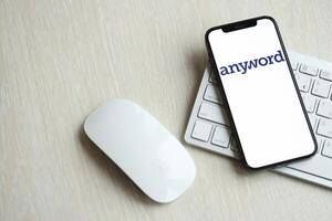 KYIV, UKRAINE - MARCH 17, 2024 Anyword logo on iPhone display screen with apple keyboard and mouse on table photo