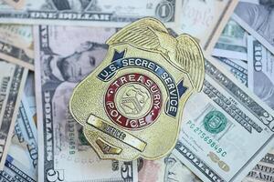 KYIV, UKRAINE - MARCH 9, 2024 US Treasury Police Secret Service Officer badge on many US dollar bills photo