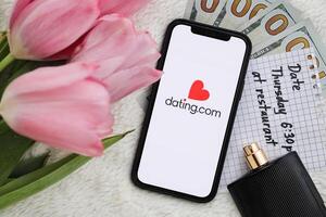 KYIV, UKRAINE - FEBRUARY 23, 2024 Datingcom logo of famous dating website or app on iPhone display photo