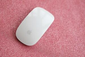 KYIV, UKRAINE - NOVEMBER 27, 2023 Apple Magic Mouse 3rd generation lies on sparkling glitter surface photo