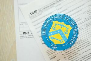 KYIV, UKRAINE - MARCH 9, 2024 US The Department of the Treasury seal on 1040 and W-2 IRS tax forms photo