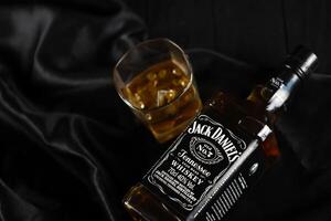 KYIV, UKRAINE - MAY 4, 2022 Jack Daniels original alcohol bottle on wooden table with black fabric photo