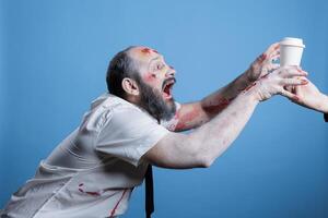 Thirsty sick junkie in need of coffee chasing it to get his fix and satisfy addiction. Businessman suffering from caffeine abuse addiction, looking like zombie without it, studio background photo